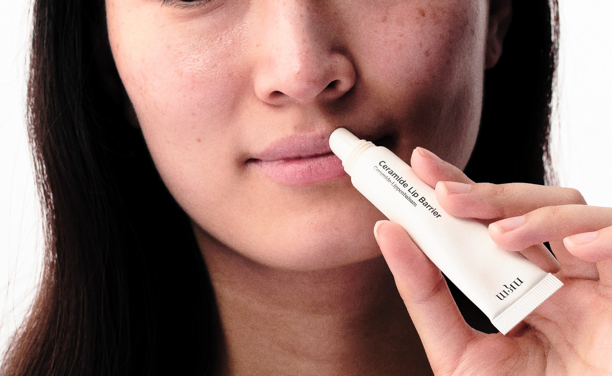 Frau hält Ceramide Lip Barrier an die Lippen