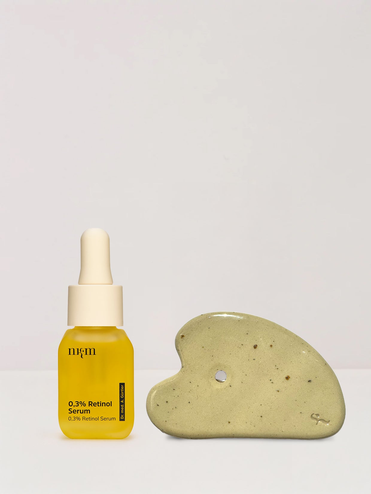 Das 0,3% Retinol Serum und der Gua Sha von nkm nebeneinander. 