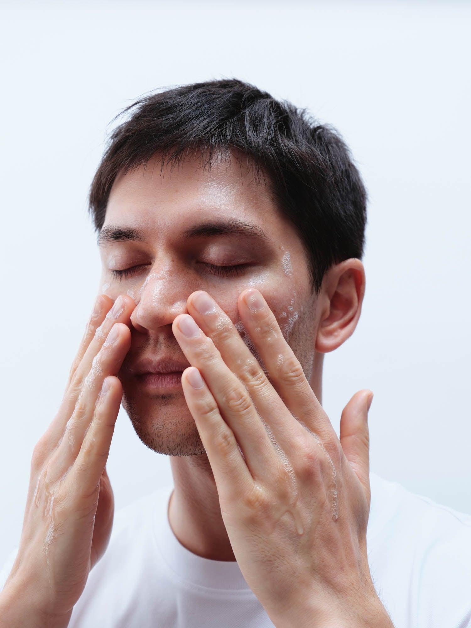 Mann mit dunklen Haaren trägt Gel Cleanser im Gesicht auf