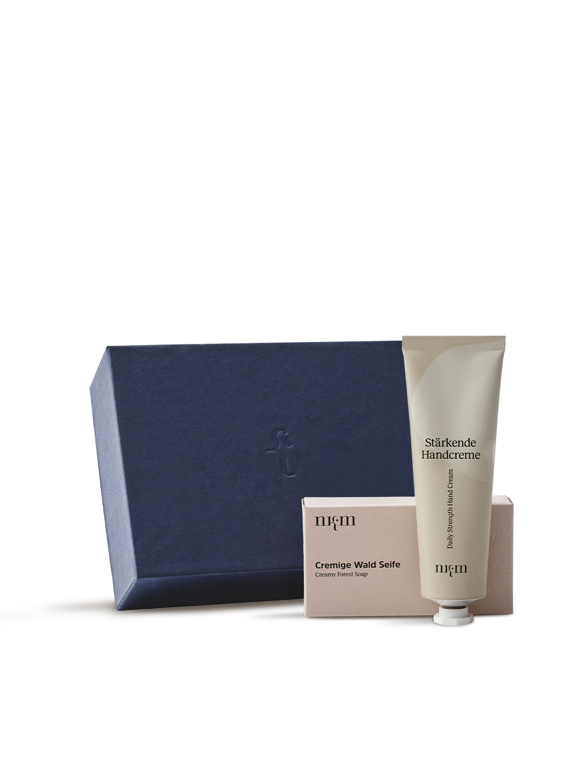 Blaue Box mit nkm Logo, davor die Cremige Wald Seife und die Stärkende Handcreme von nkm. Aufnahme vor transparentem Hintergrund