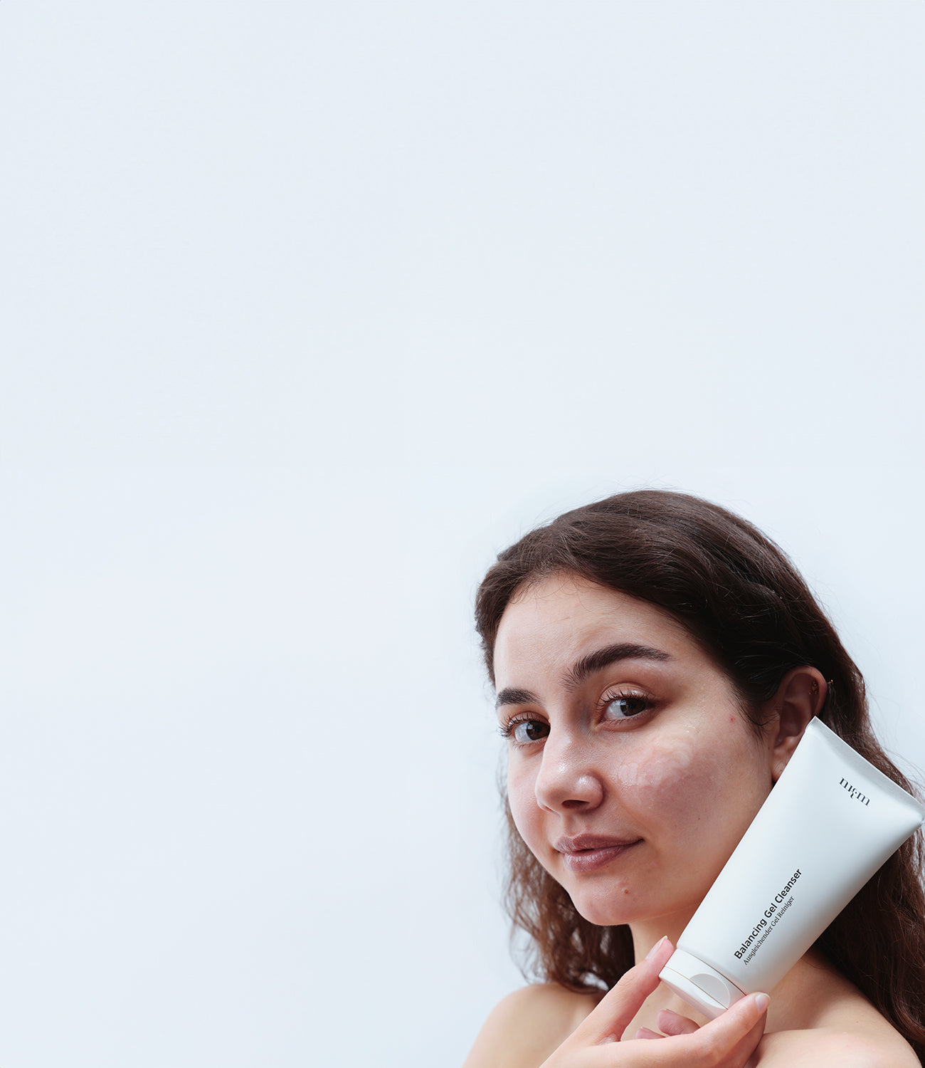 Frau mit dunklen Haaren hält Balancing Gel Cleanser in der Hand
