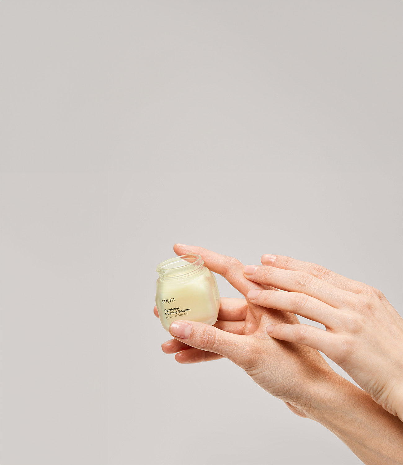 Eine Hand hält den Partiellen Peeling Balm in der Hand 